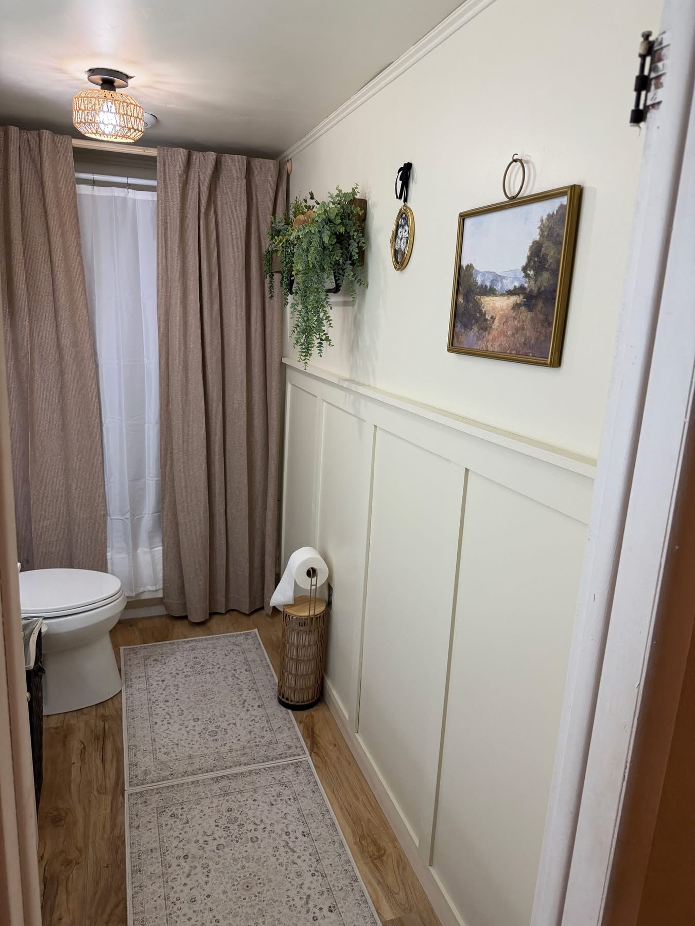 After — Bathroom with new board-and-batten wainscoting, curtains, and styled decor