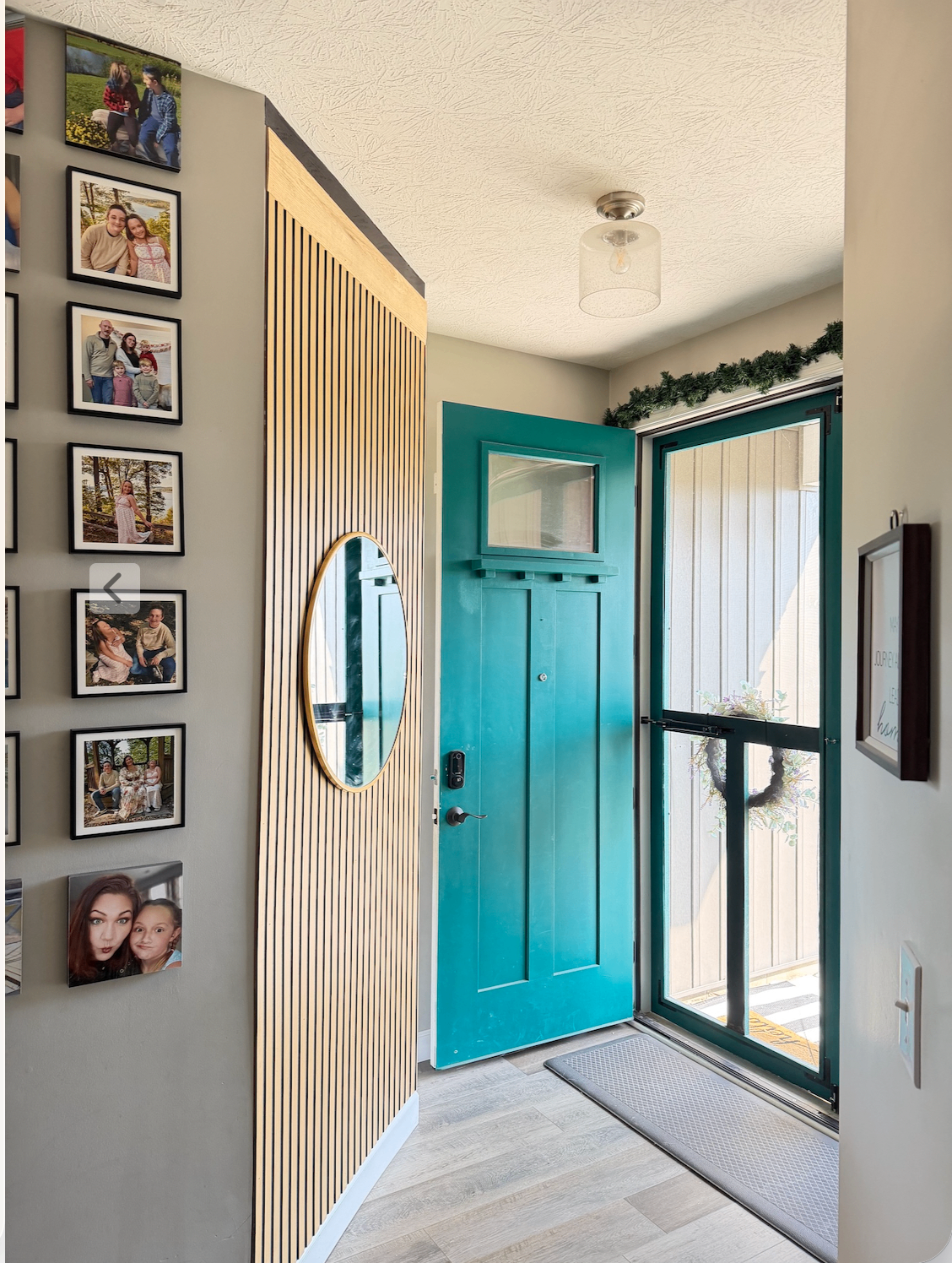 After — Entryway refreshed with a vertical wood slat accent wall, round mirror, and family photo gallery