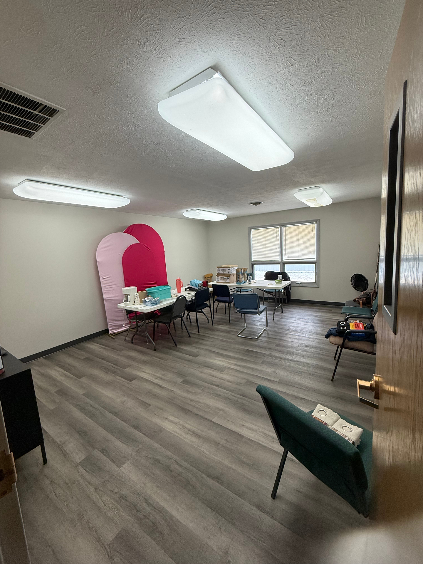 Before — Church classroom transformed into a warm, welcoming lounge with cozy seating, layered rug, and styled gallery wall