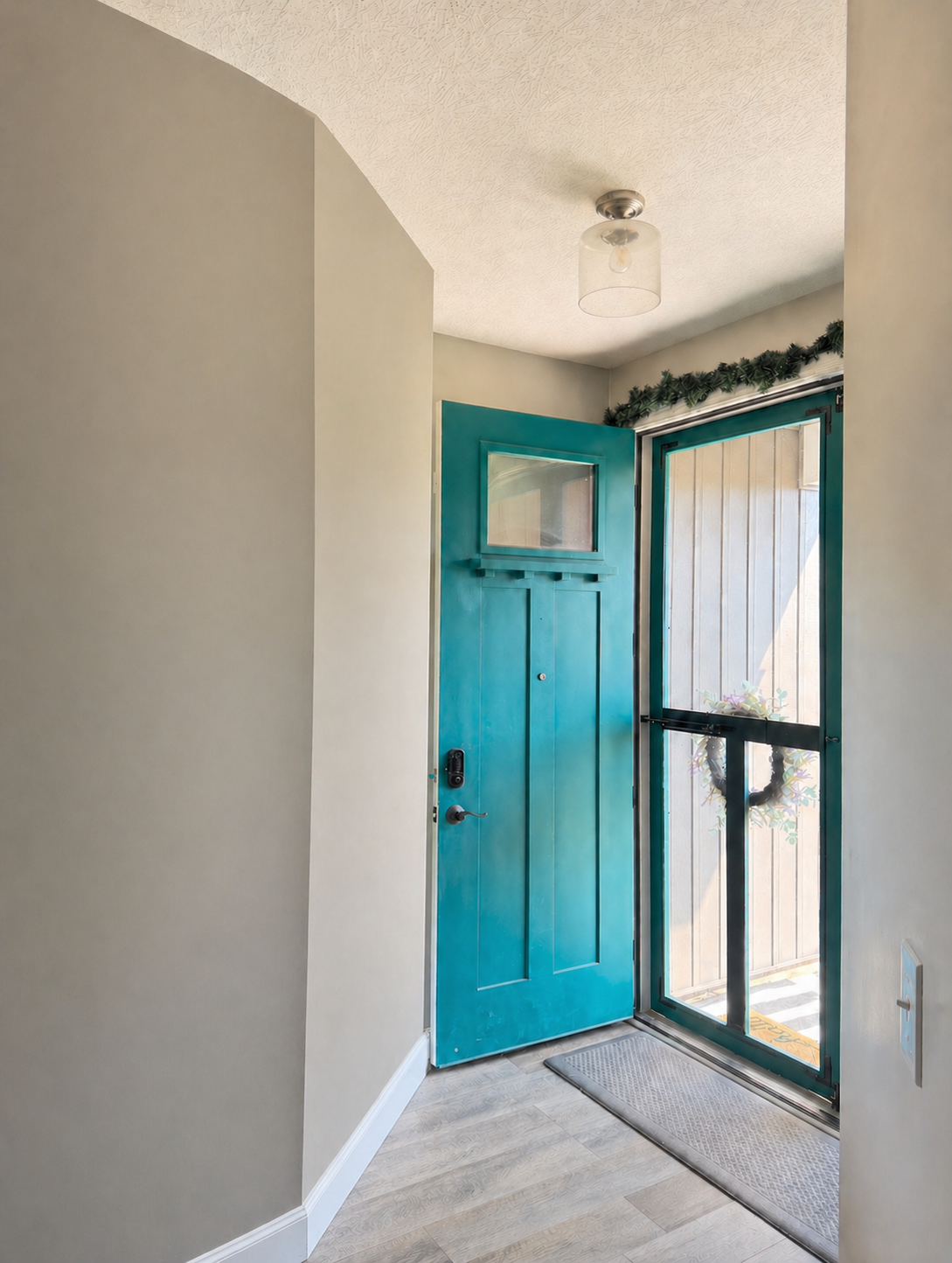Before — Entryway refreshed with a vertical wood slat accent wall, round mirror, and family photo gallery
